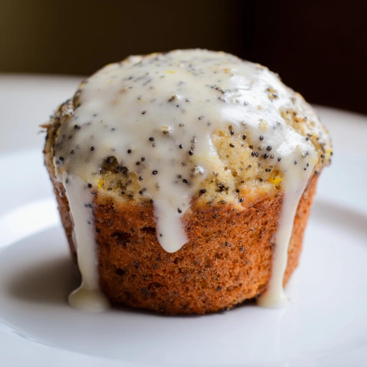 Golden brown Lemon Poppy Seed Muffins with Lemon Glaze sitting on a rustic wooden table, garnished with lemon zest.
