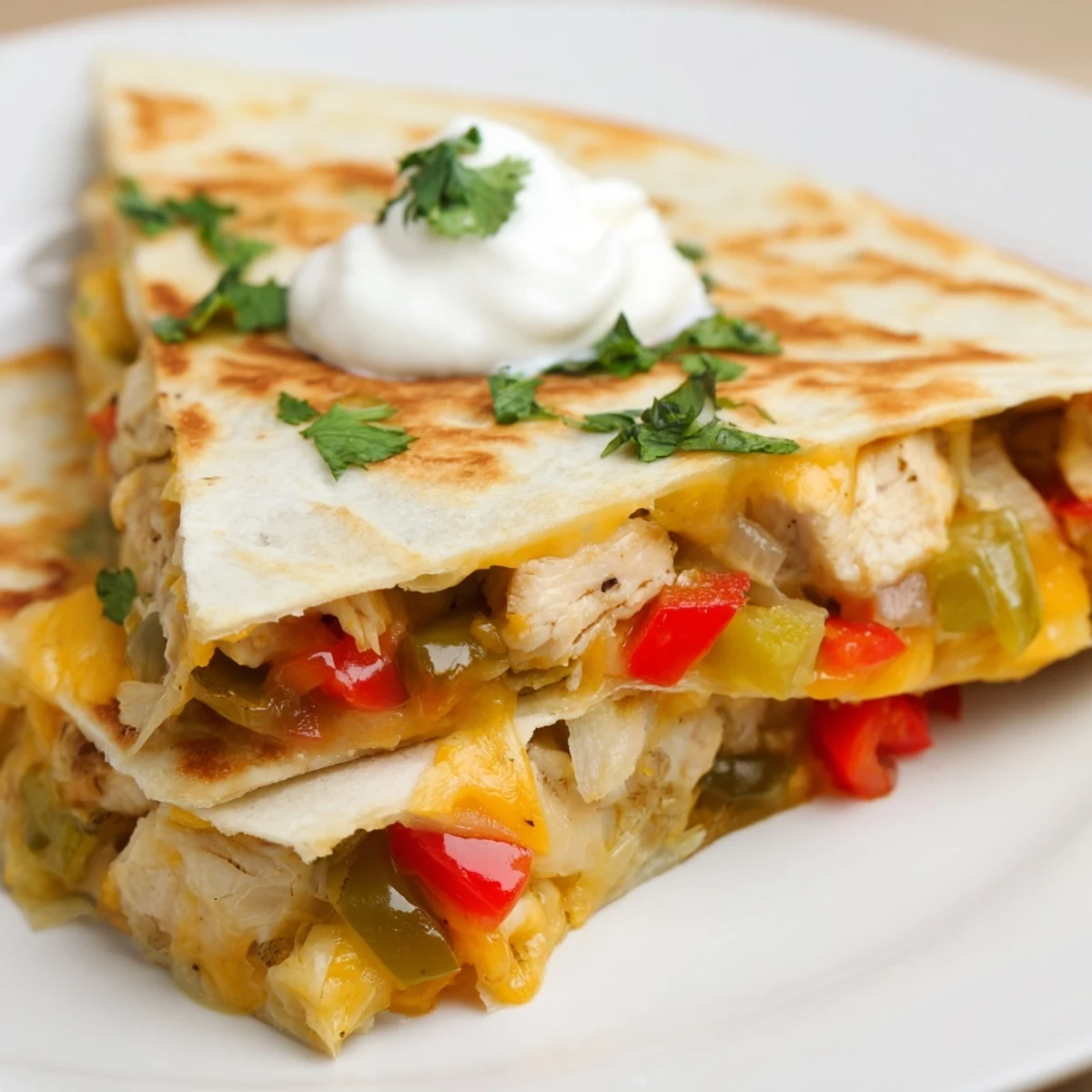Golden-brown Chicken Quesadillas with Peppers and Onions, cut into wedges on a rustic plate with fresh salsa.