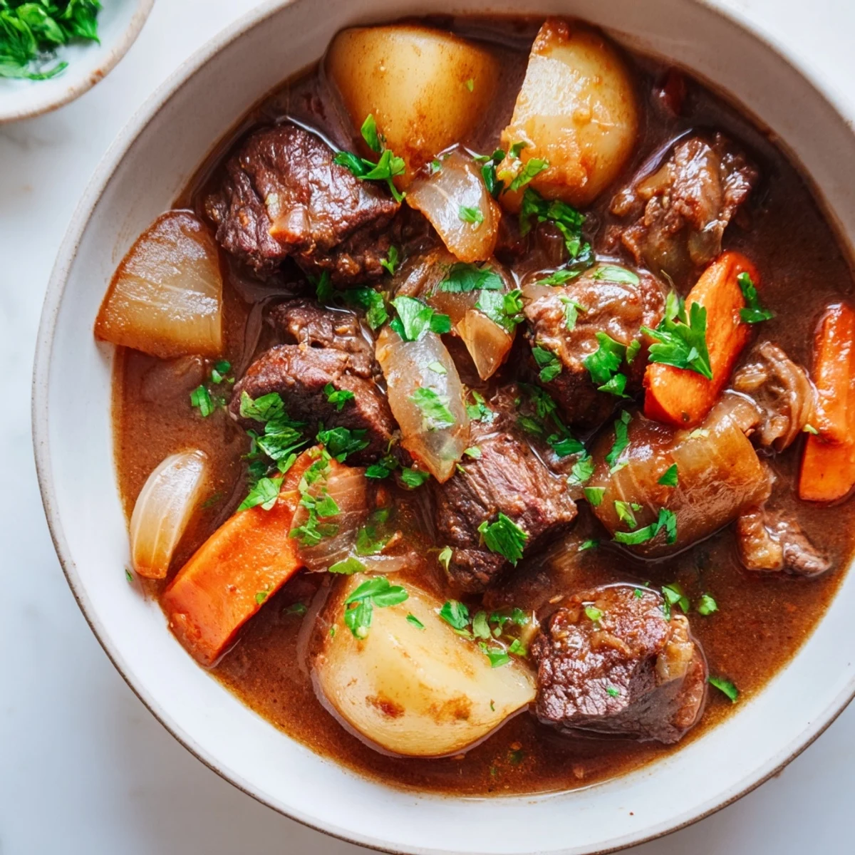 Beef and Guinness-Style Alcohol-Free Stew steaming in a rustic bowl, topped with fresh parsley.