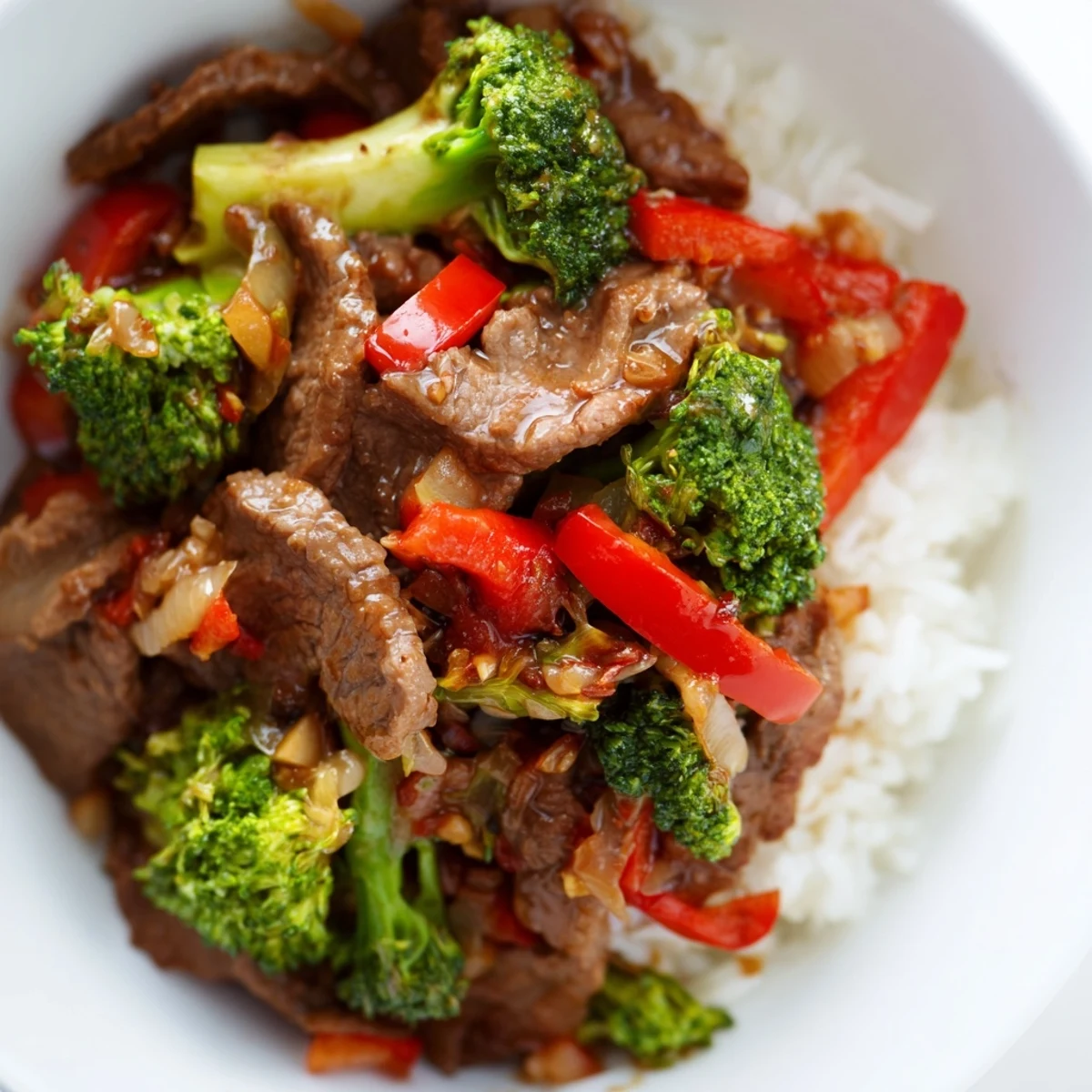 Sizzling Spicy Beef Stir Fry with Broccoli in a hot wok, mixing vibrant red bell peppers and savory brown sauce for a quick dinner.