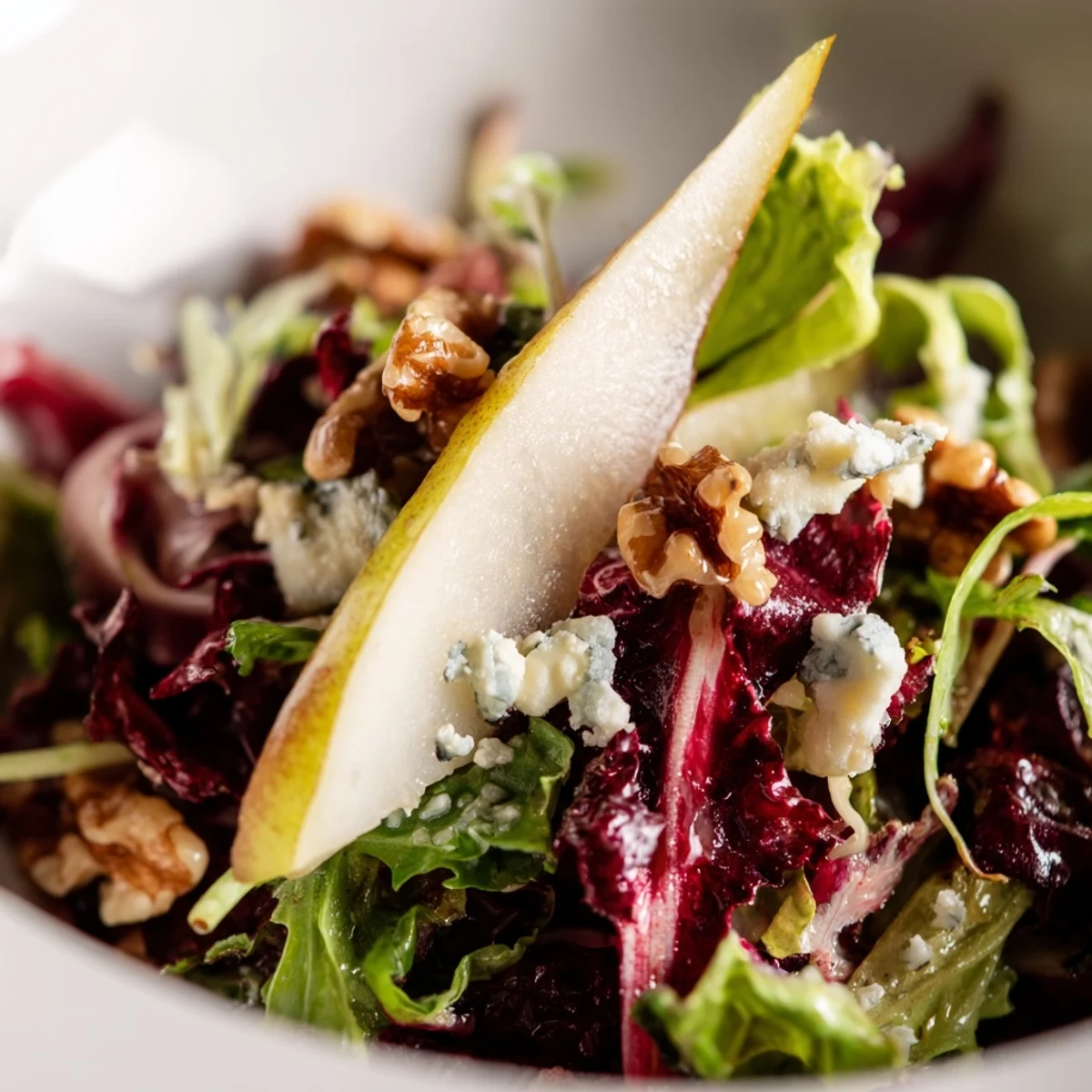 Freshly tossed Winter Green Salad with Pears in a rustic wooden bowl, topped with toasted pecans and minced shallots.