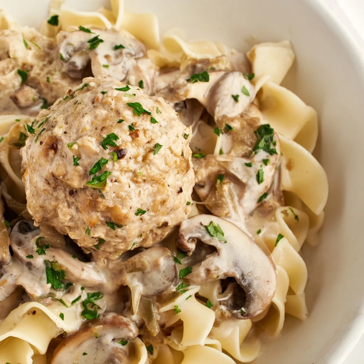 Tender turkey meatball stroganoff plated with a rich, garlicky mushroom gravy, served over steaming egg noodles for a comforting dinner.