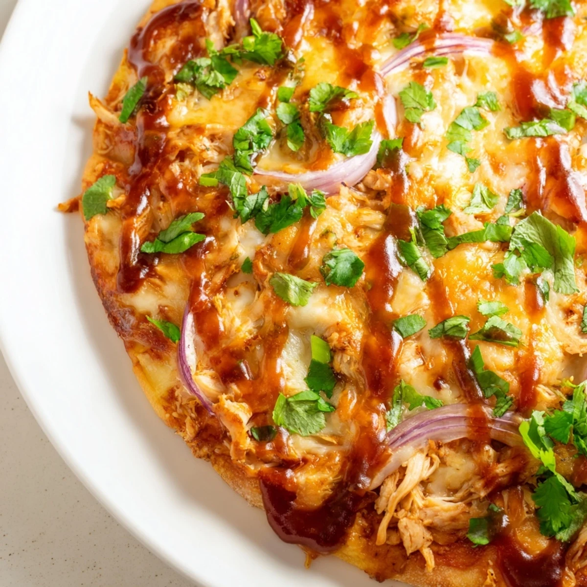 Slice of sizzling Game Day BBQ Chicken Pizza with smoky gouda, red onion, and drizzled barbecue sauce on a wooden board.  