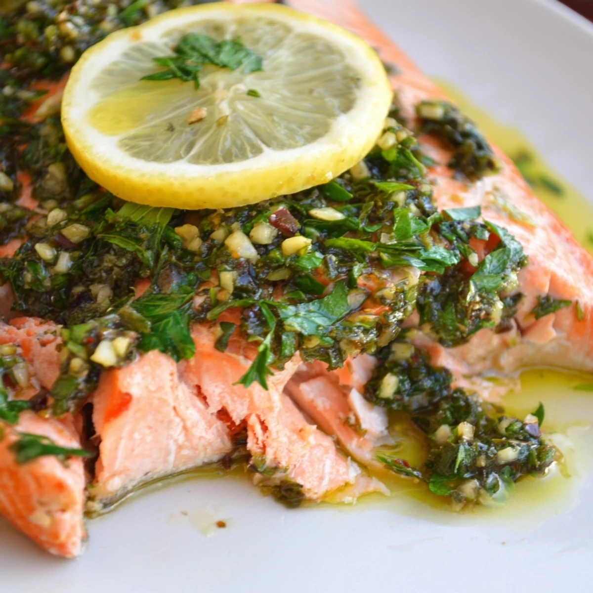 Flaky baked salmon fillet served with vibrant green salsa verde and lemon, ideal for an easy Mediterranean main dish.