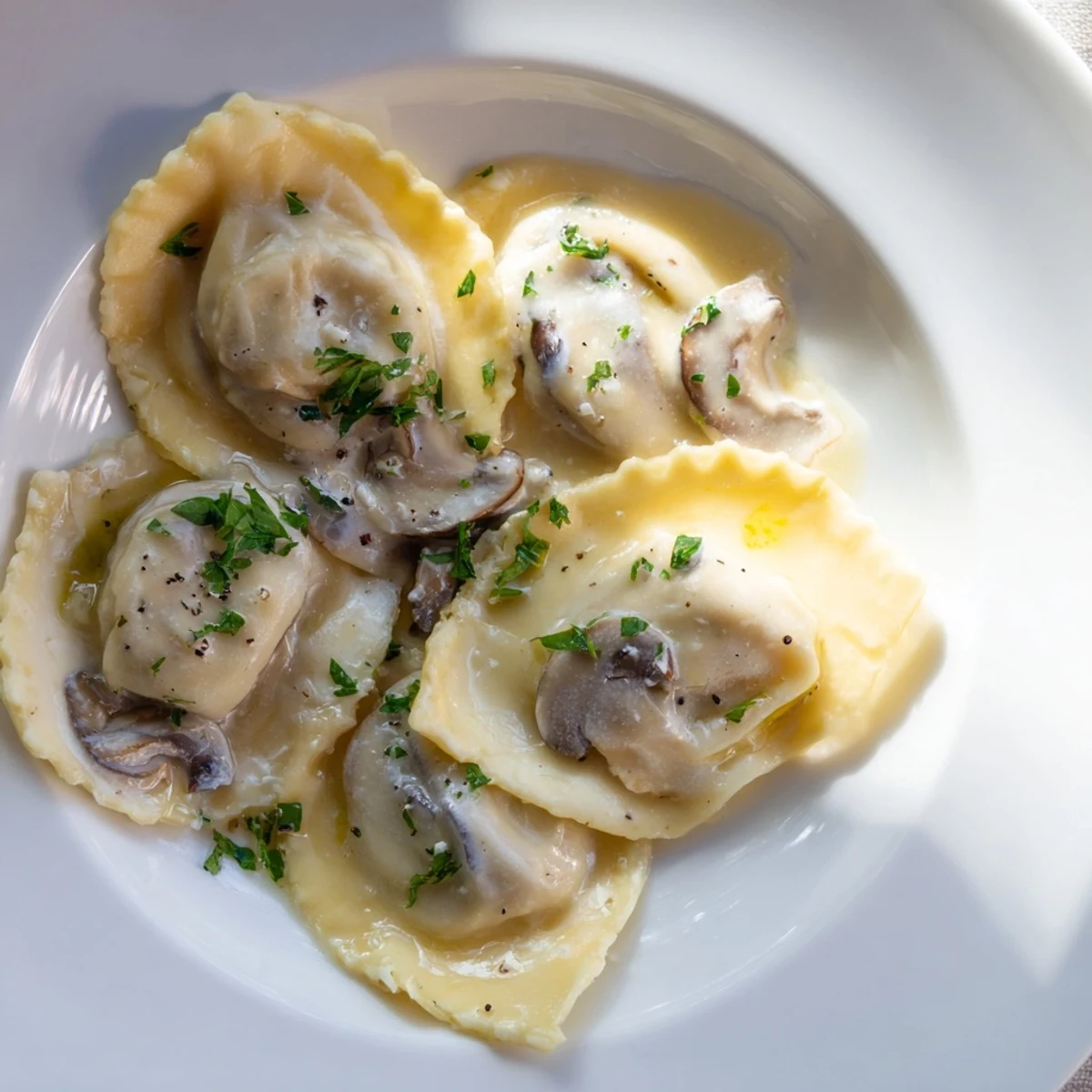 Handmade mushroom ravioli resting in a creamy Parmesan sauce, ready to be served as an elegant Italian main dish.