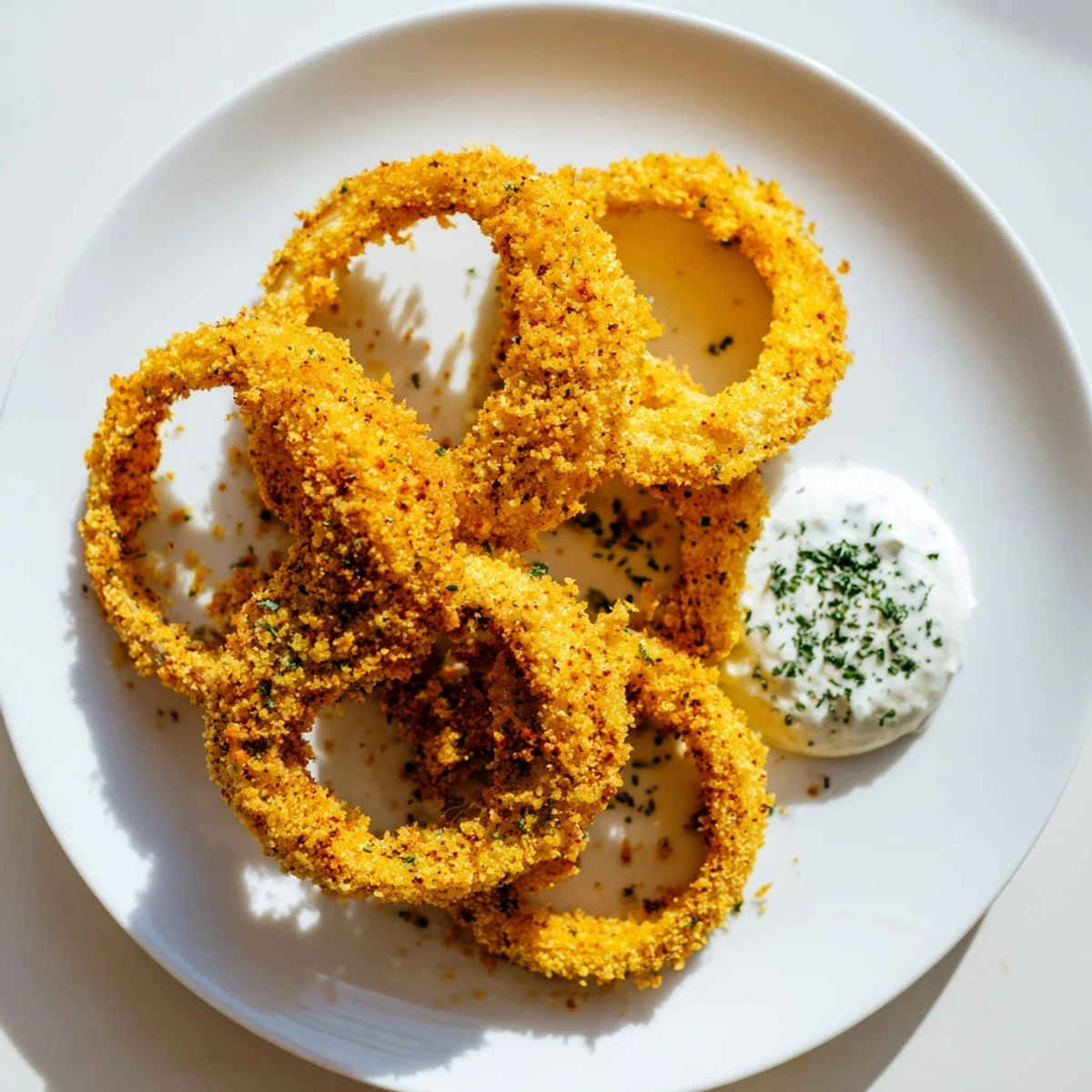 Golden, ultra-crispy Touchdown Crispy Onion Rings stacked high with a side of creamy ranch dressing, perfect for game day snacking.  