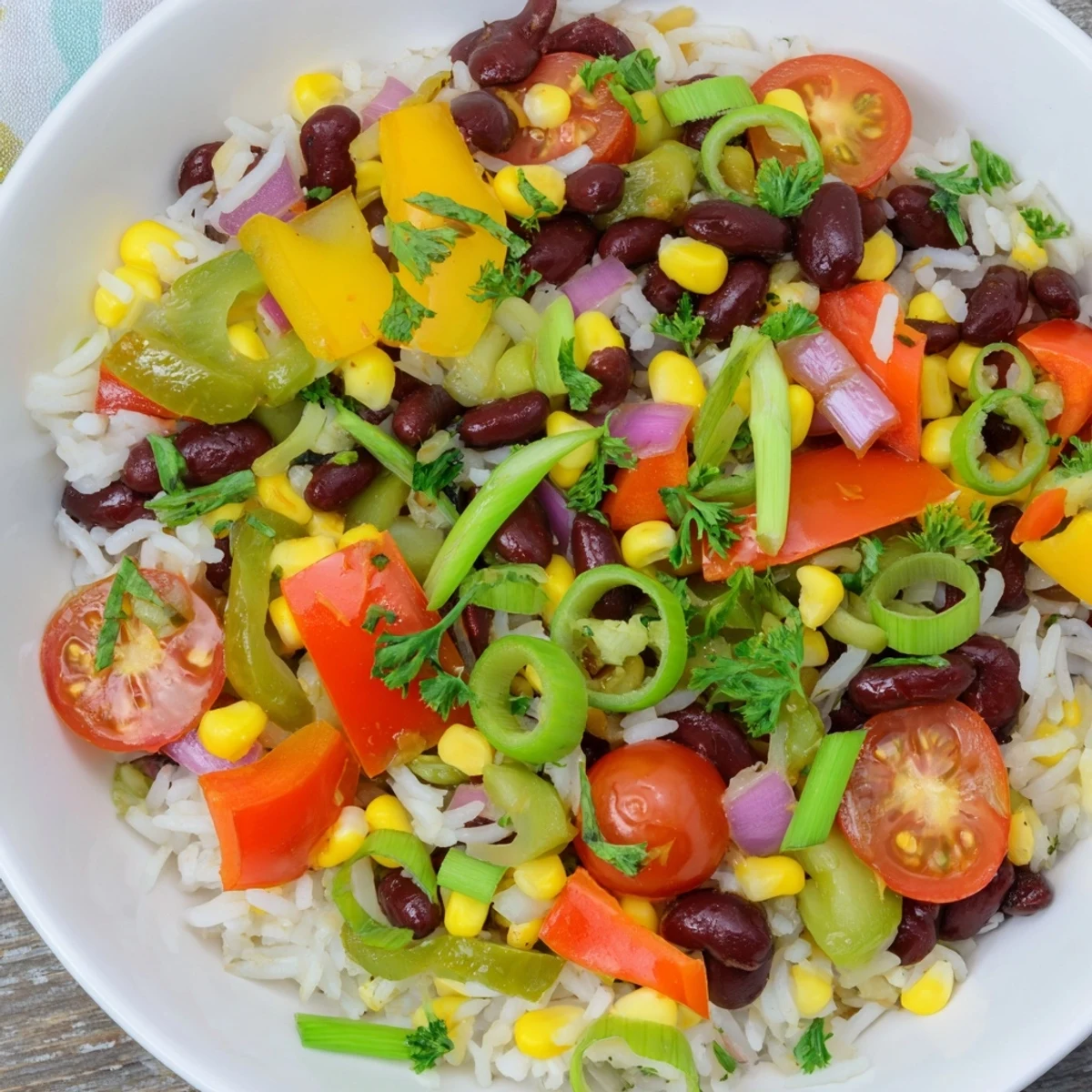 Colorful Mardi Gras Veggie Rice Bowl topped with fresh herbs and zesty lime wedges.