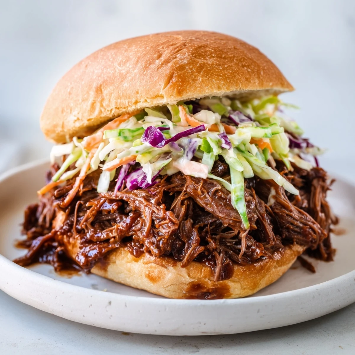 Freshly shredded Tailgate Pulled Beef Sliders piled high on soft buns with tangy slaw.