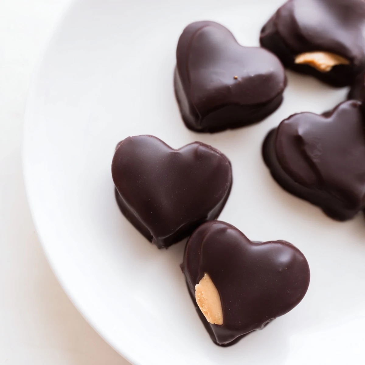 Homemade chocolate peanut butter hearts arranged on a marble surface, showcasing their rich color and perfectly defined heart shape.