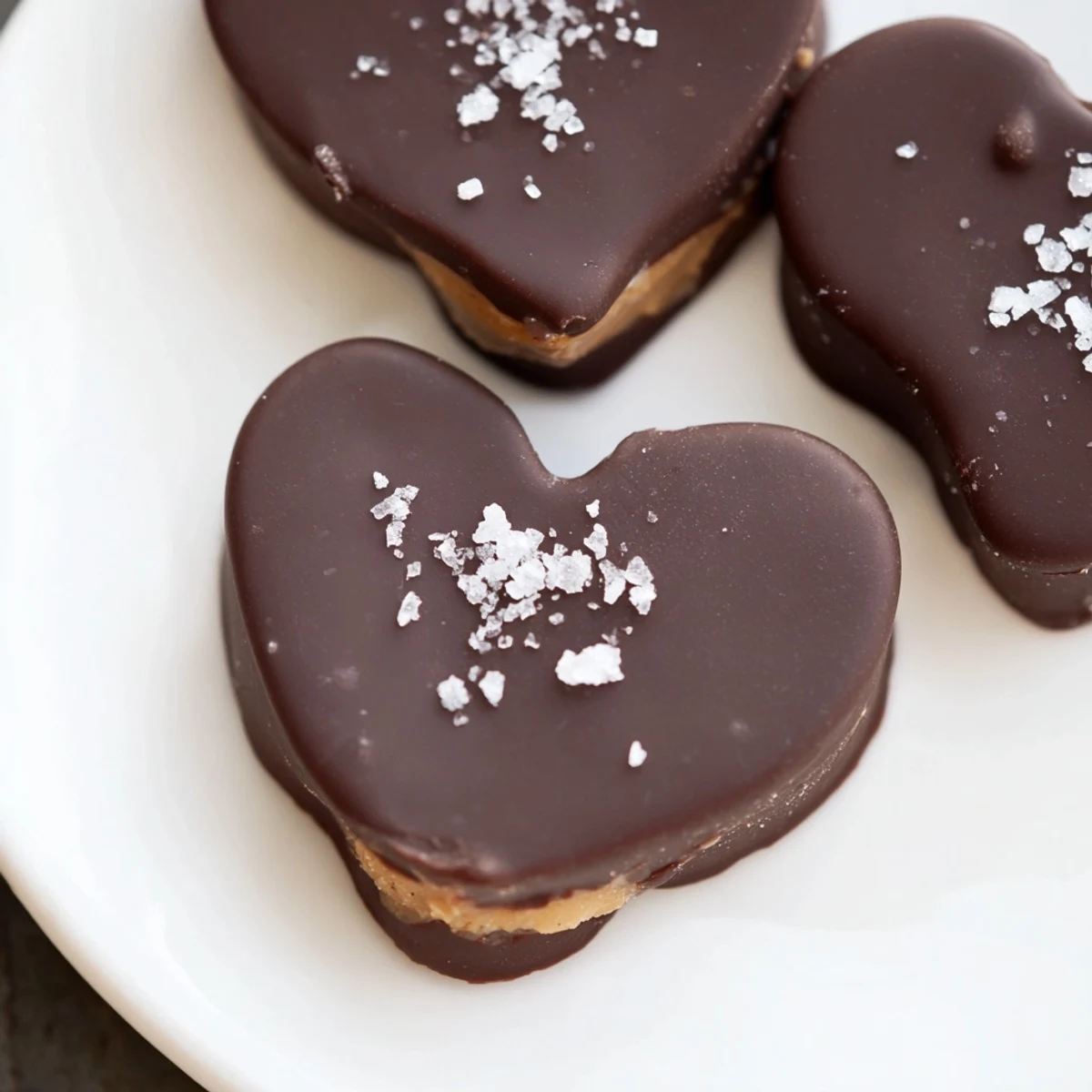 Freshly dipped chocolate peanut butter hearts with sea salt, arranged on parchment paper for easy serving.