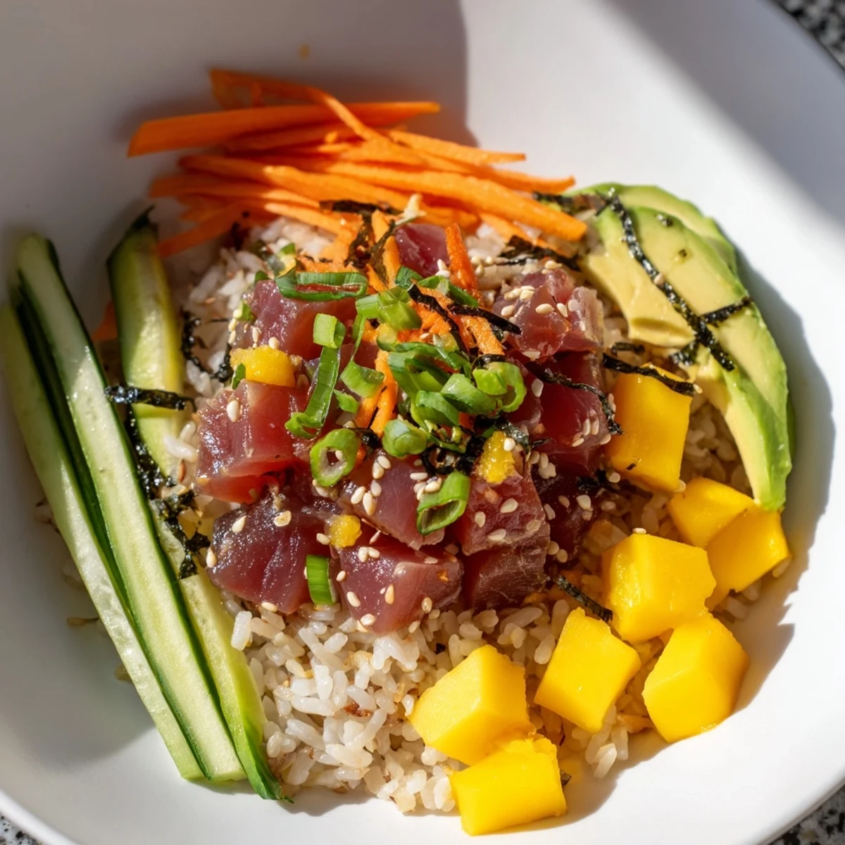 A vibrant Spicy Tuna Poke Bowl with Mango includes nori strips, pickled ginger, and sriracha drizzle for extra heat and texture.