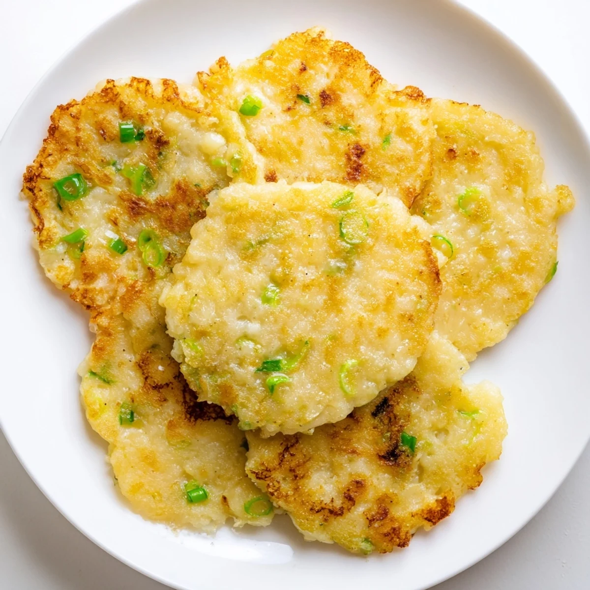 These golden brown Irish Boxty Potato Pancakes with Scallions are stacked high on a rustic plate, ready to be served.