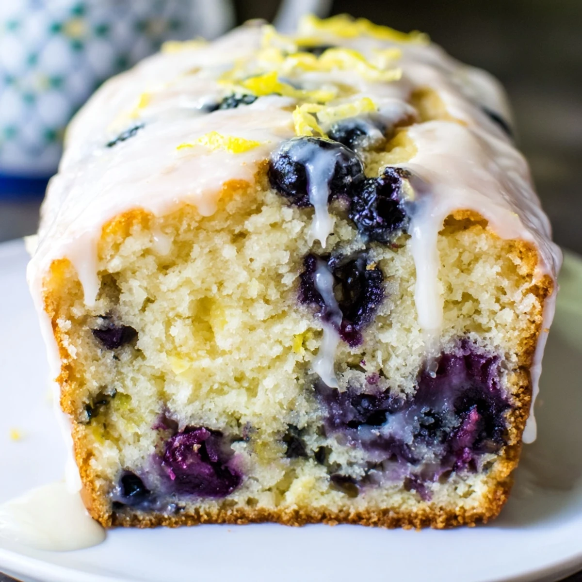 Fresh Lemon Blueberry Yogurt Loaf Cake with Glaze slice showing tender crumb, lemon zest, and a drizzle on top.