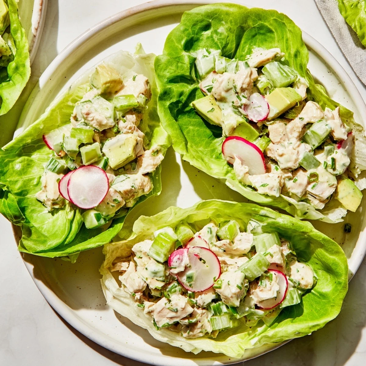 Green Goddess Chicken Salad Lettuce Wraps served fresh with diced avocado and crunchy radish slices.