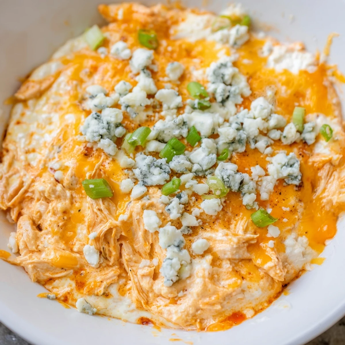 A close-up of Keto Buffalo Chicken Dip showing shredded chicken, spicy buffalo sauce, and a melted mozzarella and cheddar topping.