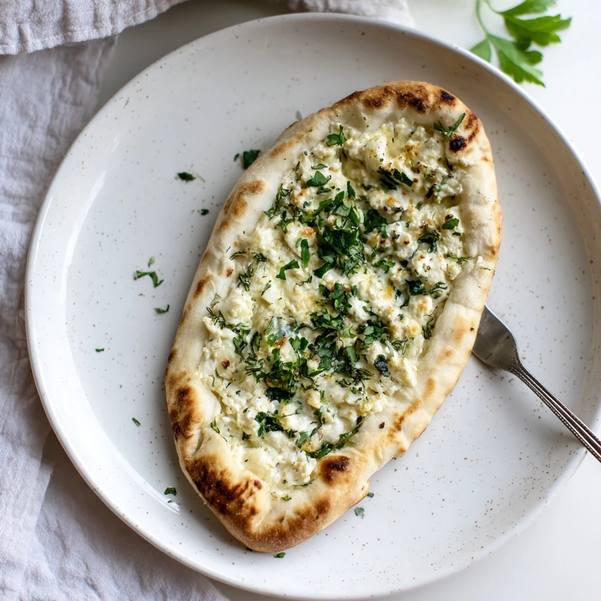 Cottage Cheese Garlic Naan stuffed with creamy cottage cheese, served warm alongside a bowl of rich Indian curry.