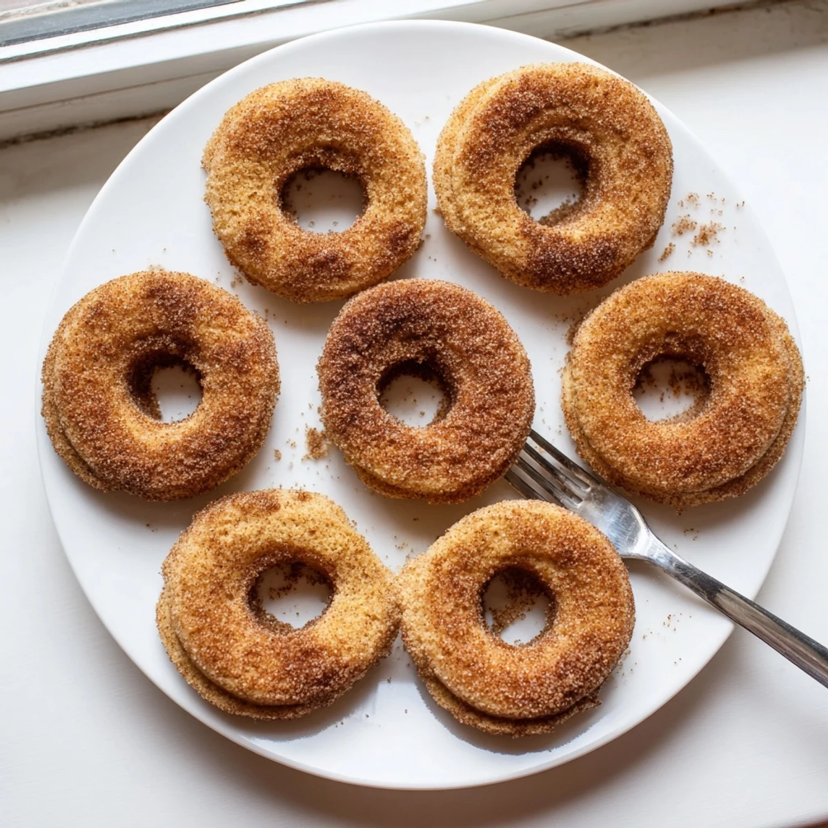 Freshly rolled Delicious Baked Cinnamon Sugar Donuts are paired with a steaming mug of hot coffee.