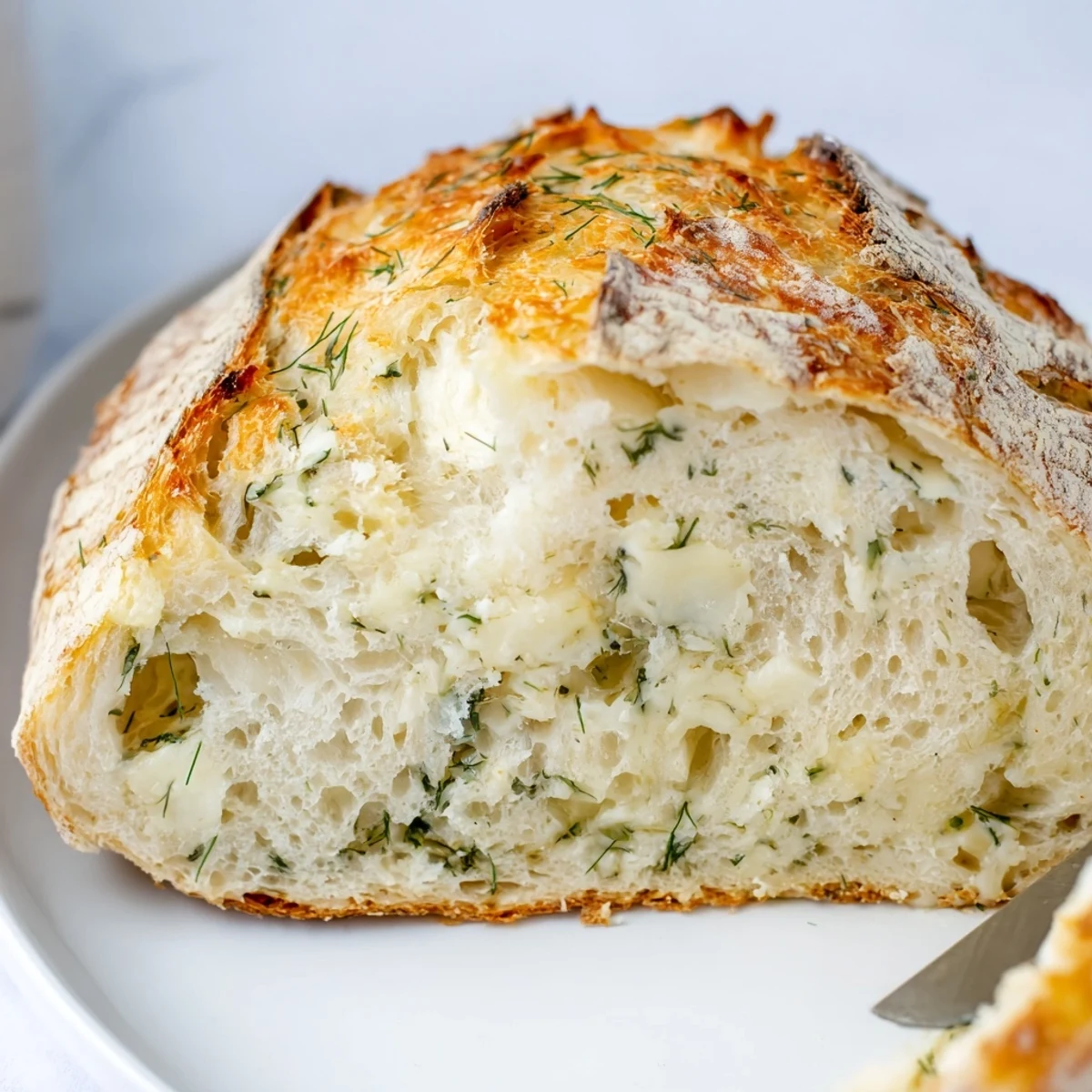 Slice of No Knead Dill Gouda Artisan Bread showing a soft, airy crumb with melted Gouda, served beside a steaming bowl of tomato soup.