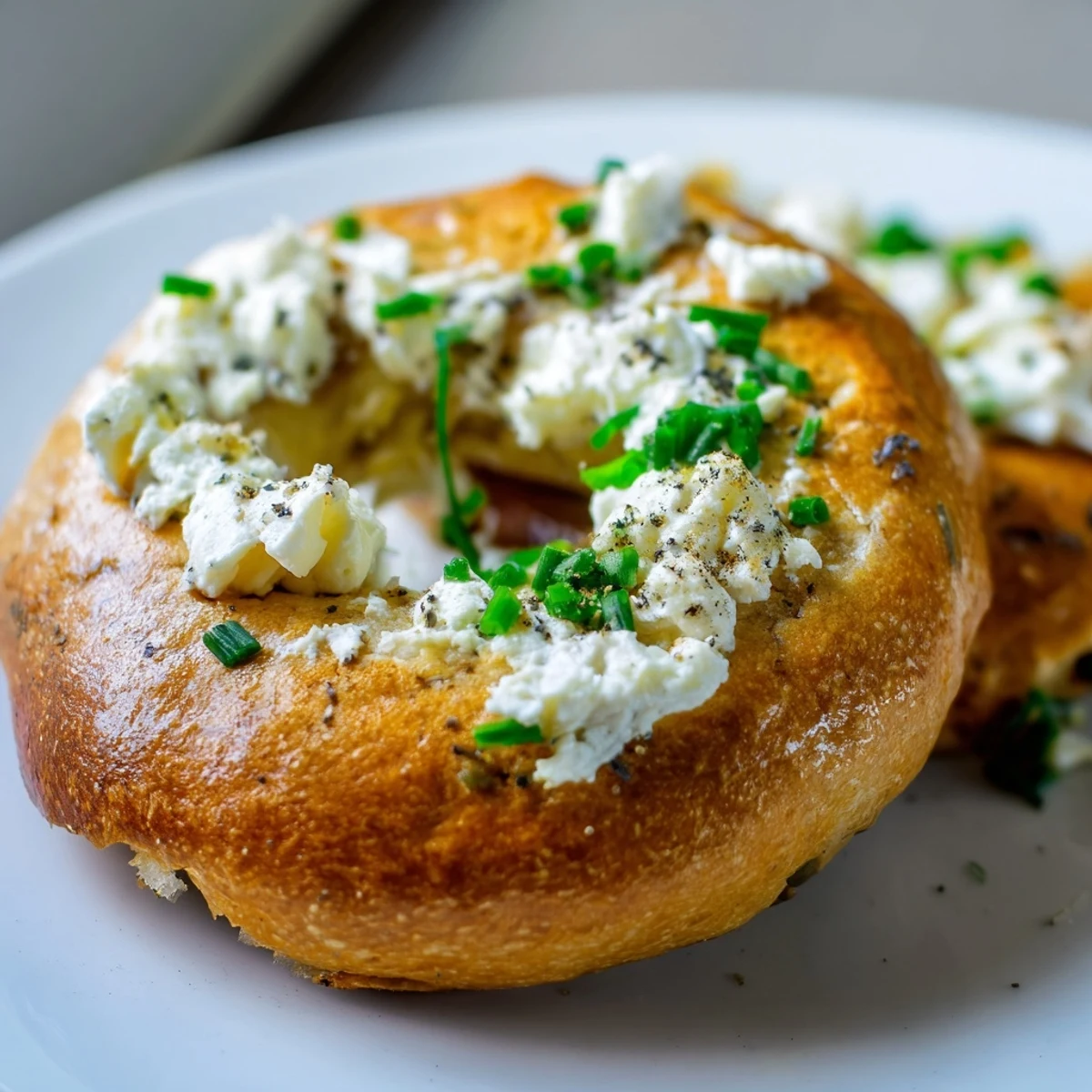 A rustic kitchen scene featuring Protein Bagels with Cottage Cheese, garnished with black pepper and chives for a savory breakfast.