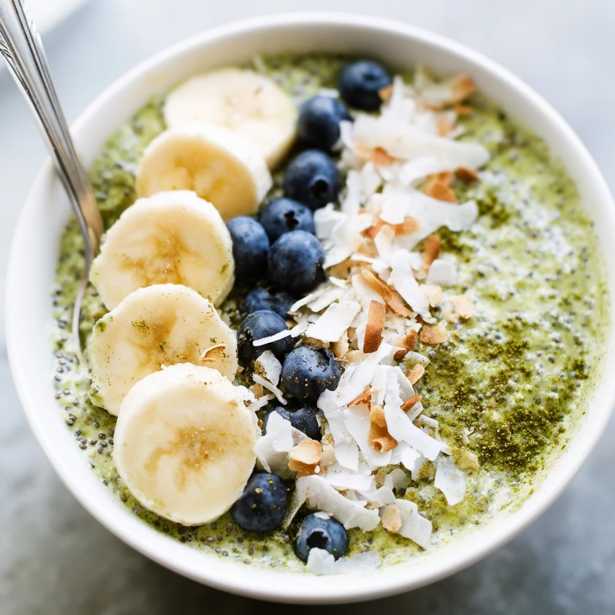 Prepared matcha protein overnight oats recipe in mason jars with fresh berries on a marble countertop.