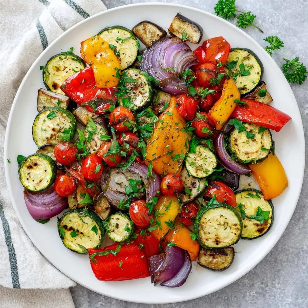 A close-up of Italian Roasted Vegetables glistening with olive oil and herbs on a baking sheet, served warm as a healthy side dish.