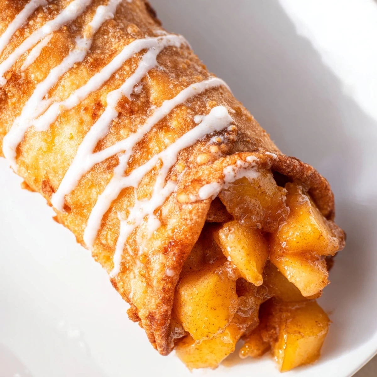Golden baked Peach Cobbler Egg Rolls arranged on a rustic wooden board with a sweet glaze drizzle.