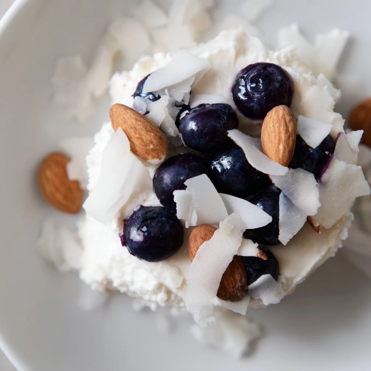 Frozen Blueberry Greek Yogurt Bites topped with shredded coconut on a white plate.