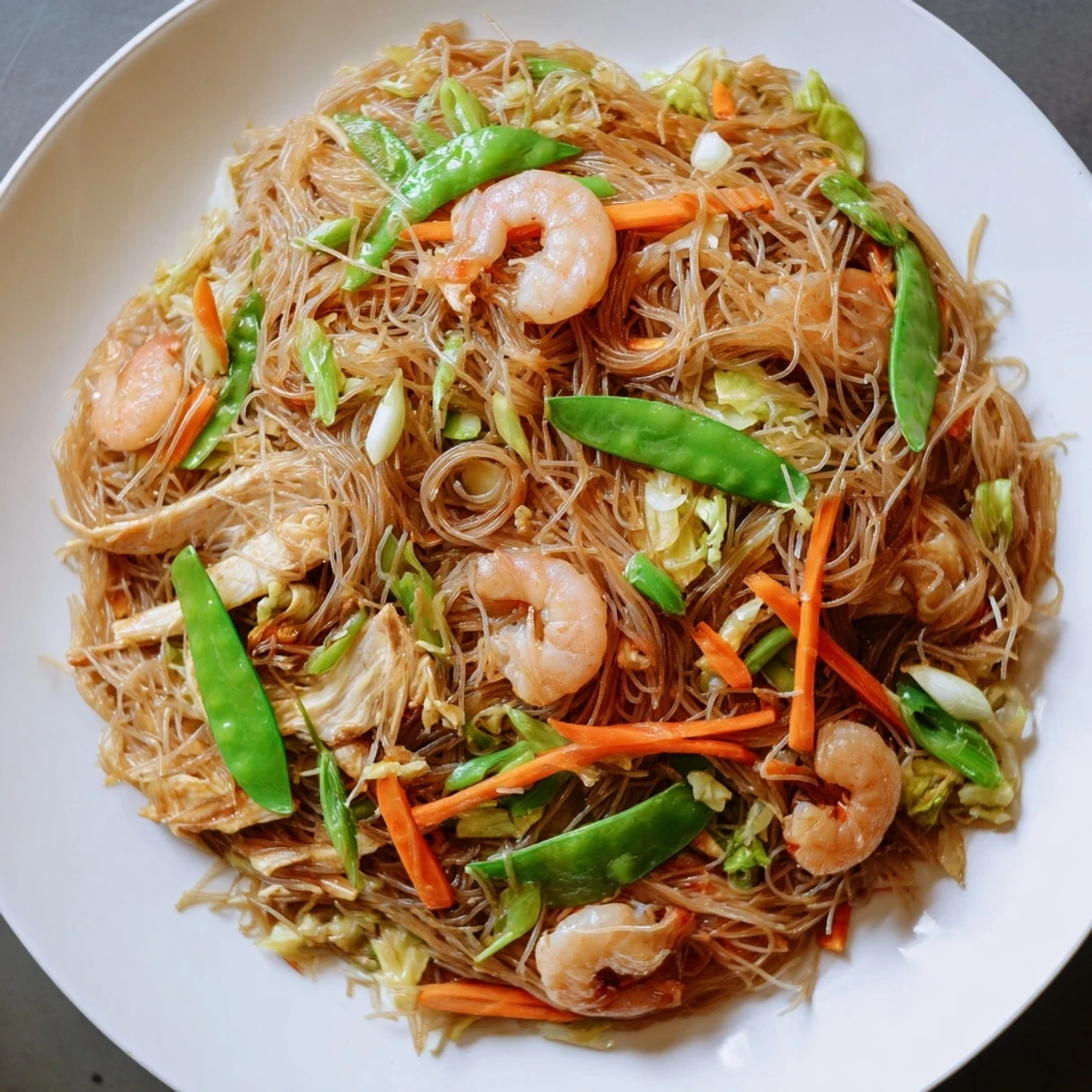 Festive Filipino Pancit Bihon noodle dish garnished with crisp cabbage and carrot julienne