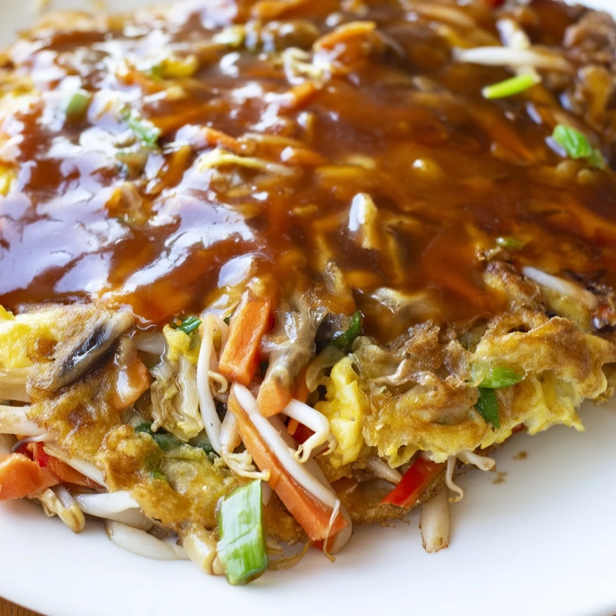 Chinese-American Egg Foo Young served hot with drizzled sauce over crispy edges
