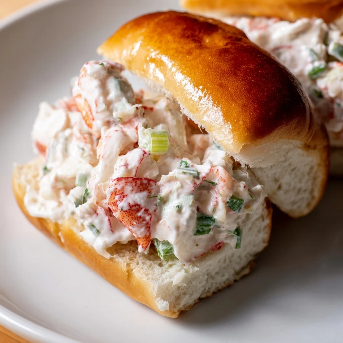Golden toasted brioche rolls overflowing with creamy garlic butter lobster rolls topped with fresh herbs