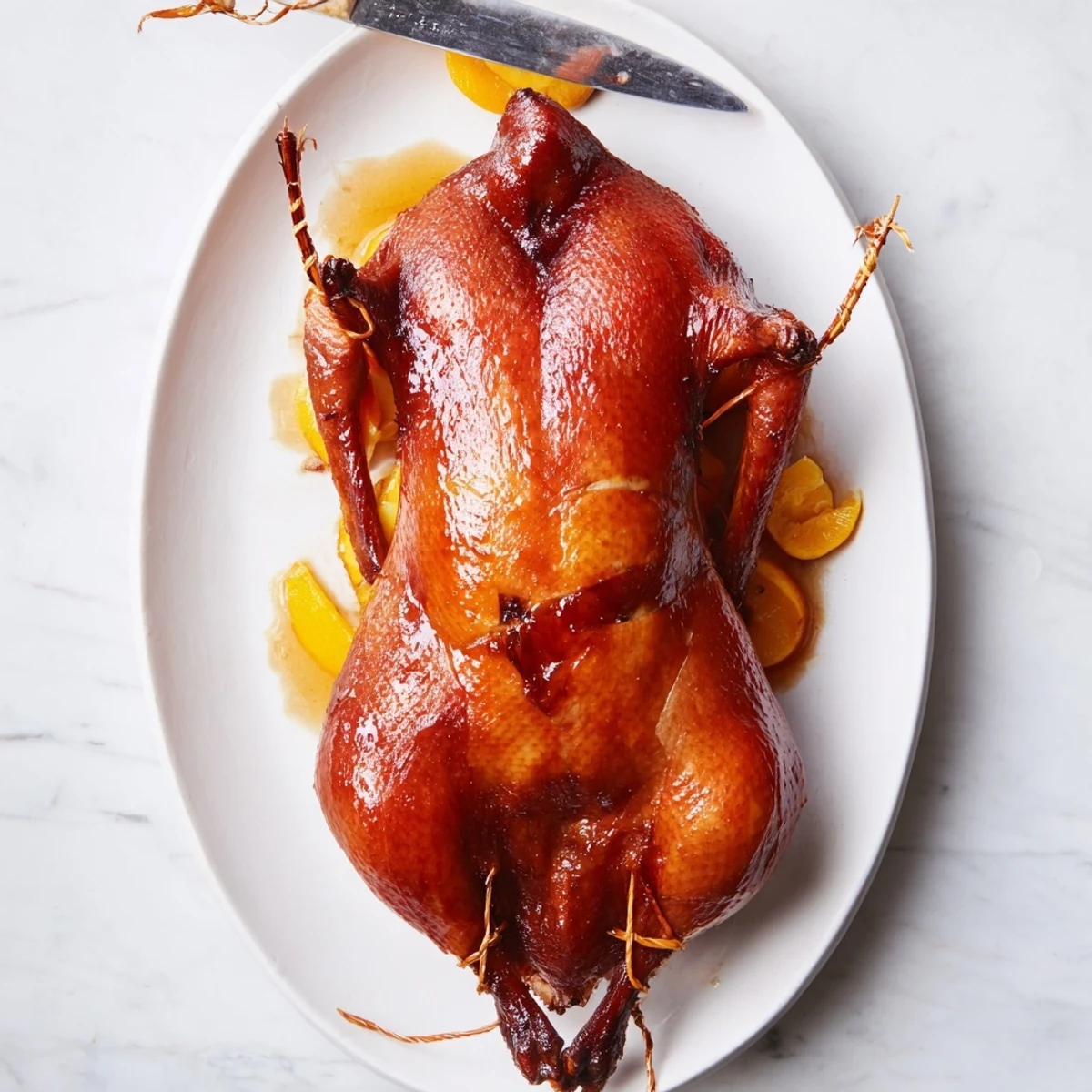 Golden brown five spice roasted duck with crispy glistening skin on a white serving platter