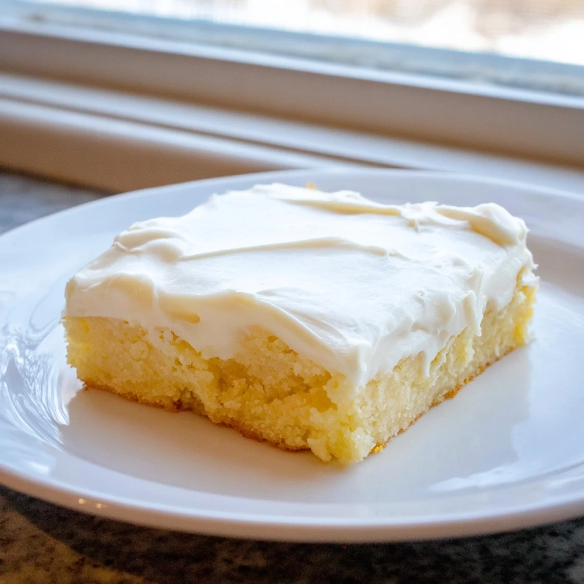 Soft baked sugar cookie bars topped with fluffy white frosting and colorful rainbow sprinkles
