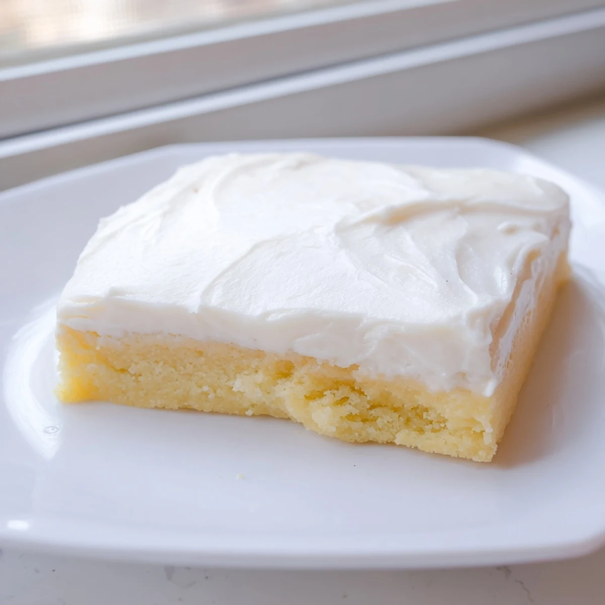 Golden sugar cookie bars sliced into squares spread with creamy vanilla buttercream frosting