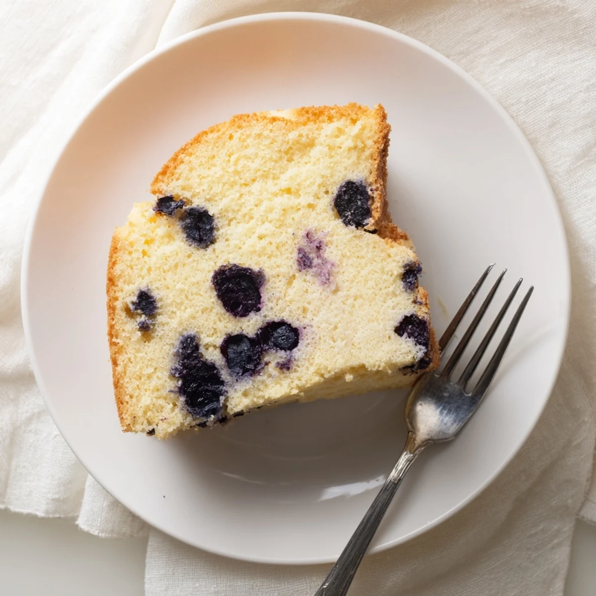 Light and airy chiffon cake studded with juicy blueberries and zesty lemon on a wooden board