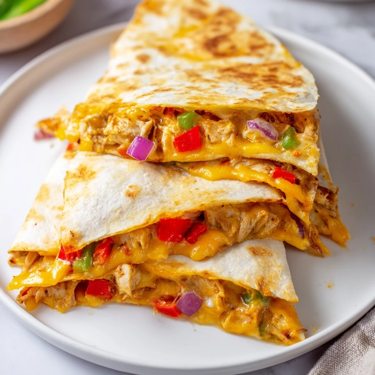 Crispy flour tortilla quesadillas filled with seasoned chicken and vegetables cut into triangular wedges