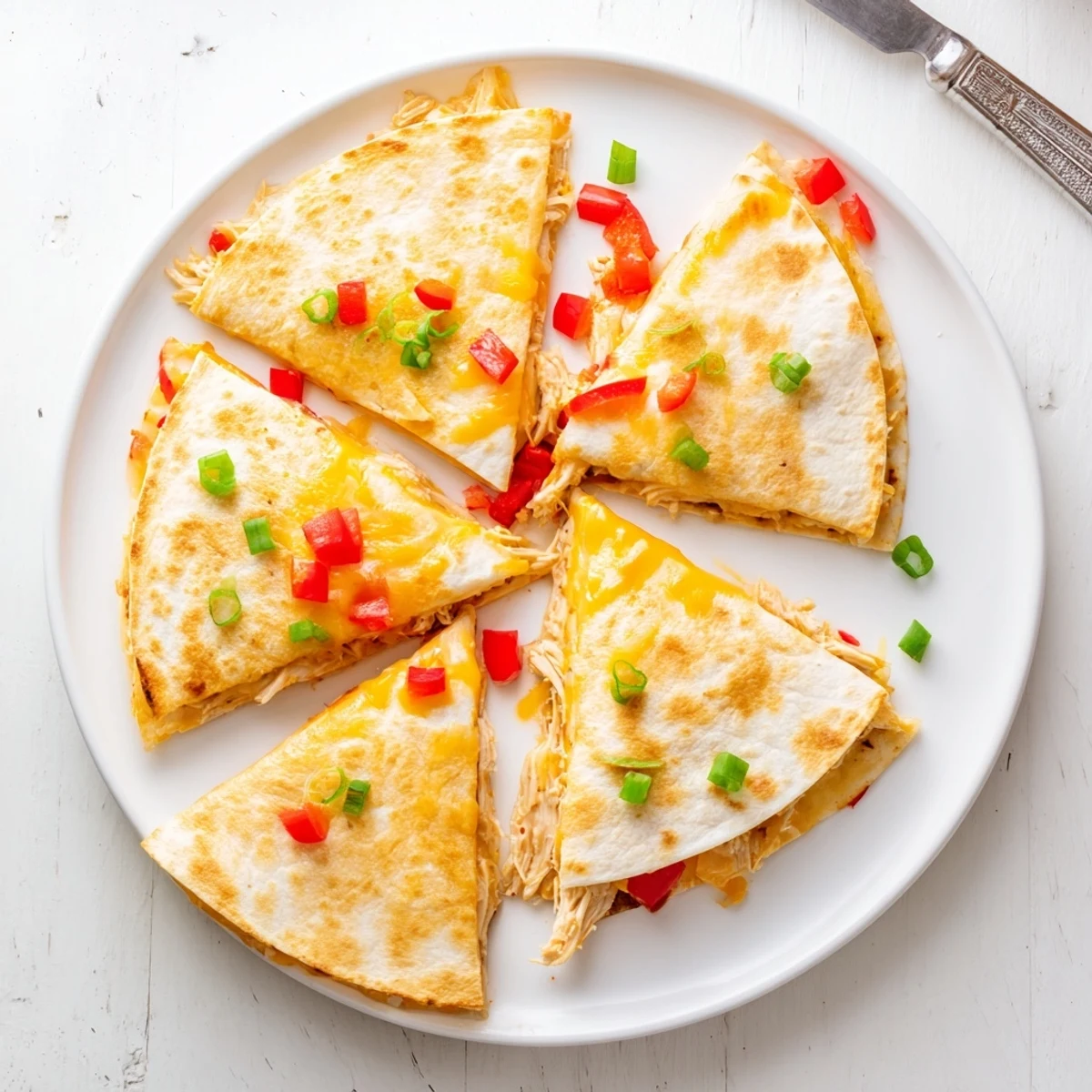 Golden baked chicken and cheese quesadillas cut into wedges on a white serving plate