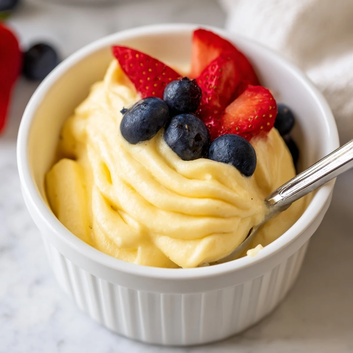 Golden Italian zabaglione custard served warm in elegant glass bowls with fresh berries