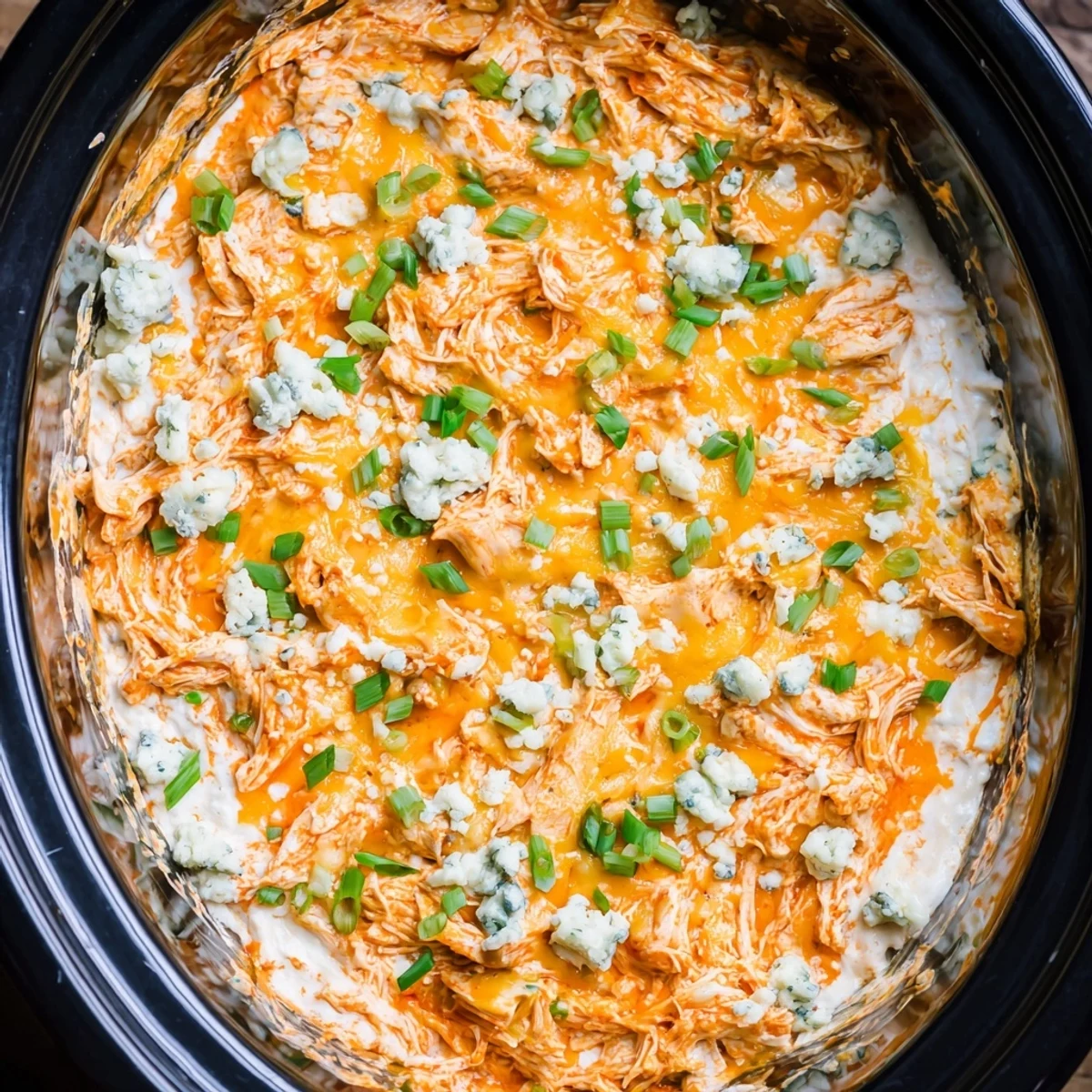 Steamy slow cooker buffalo chicken dip topped with fresh green onions and blue cheese