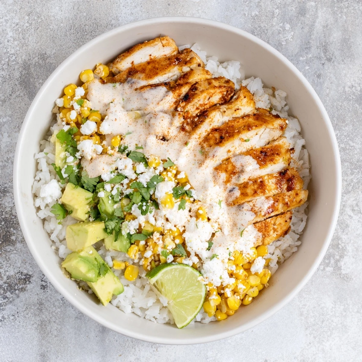 Golden grilled chicken atop fluffy rice with sweet charred corn, creamy cotija sauce, and fresh cilantro in this street corn chicken rice bowl