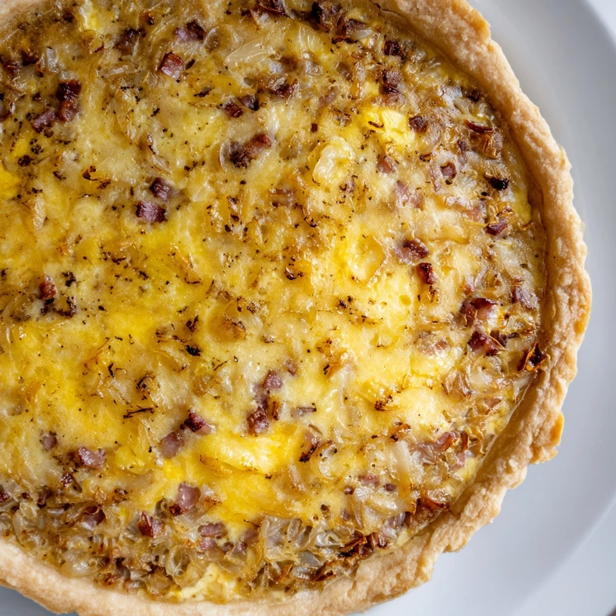 Warm German onion pie wedges served on a white plate with a crisp green salad side