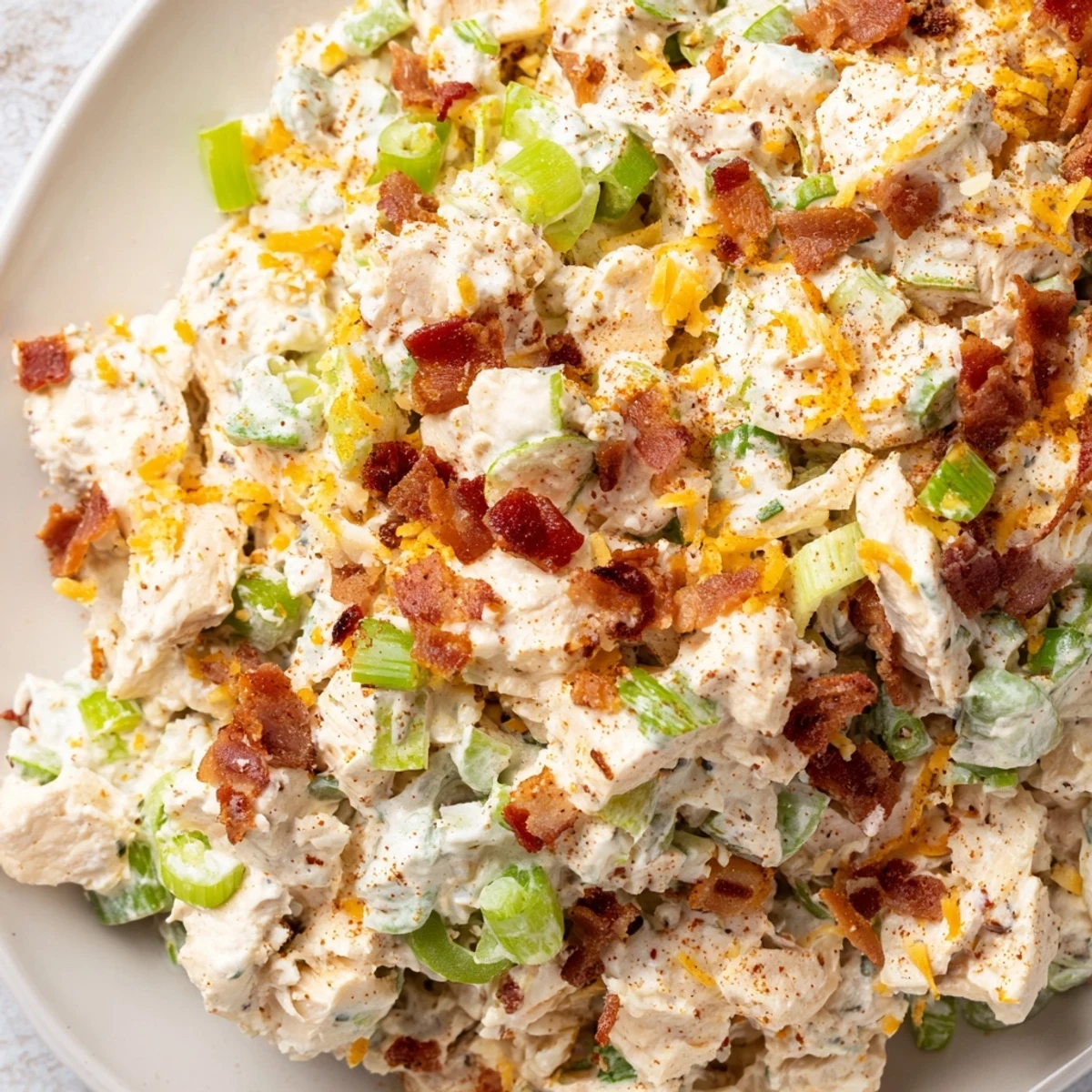 Spoonful of spicy jalapeno popper keto chicken salad with crisp celery bits and green onion garnish on rustic wooden surface