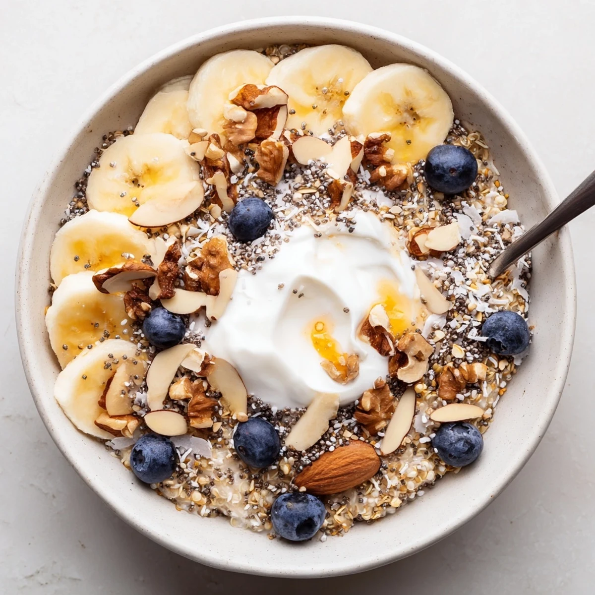 Creamy blueberry quinoa breakfast bowl topped with fresh bananas, crunchy nuts, and chia seeds
