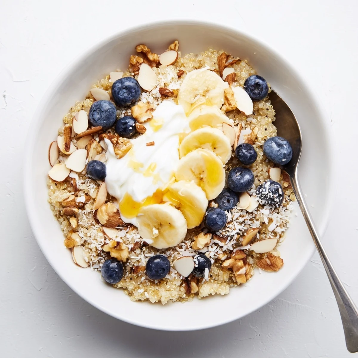 Protein-packed blueberry quinoa breakfast bowl arranged with coconut flakes, sliced banana, and almond toppings