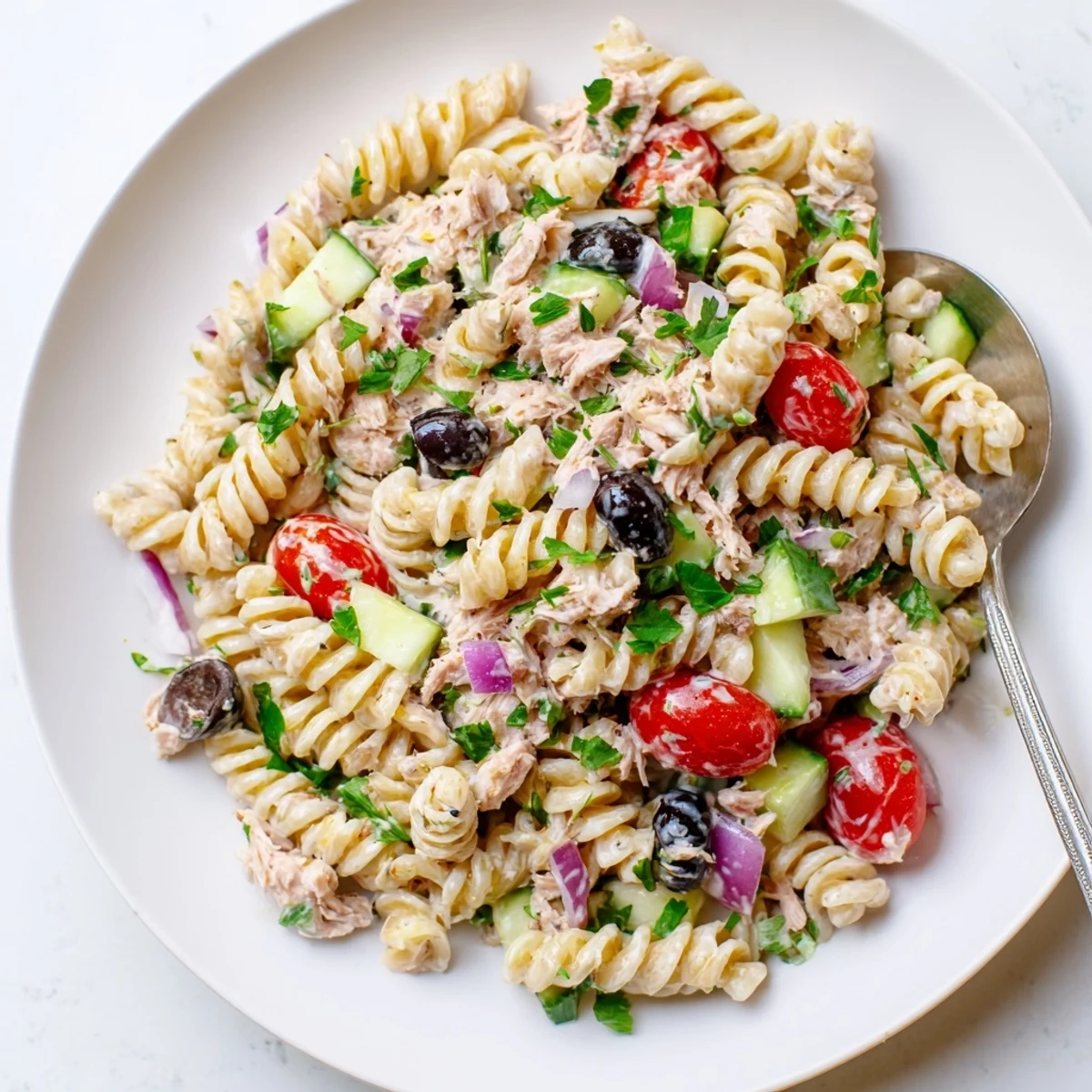 Creamy tuna pasta salad in a white bowl with cherry tomatoes and crisp celery