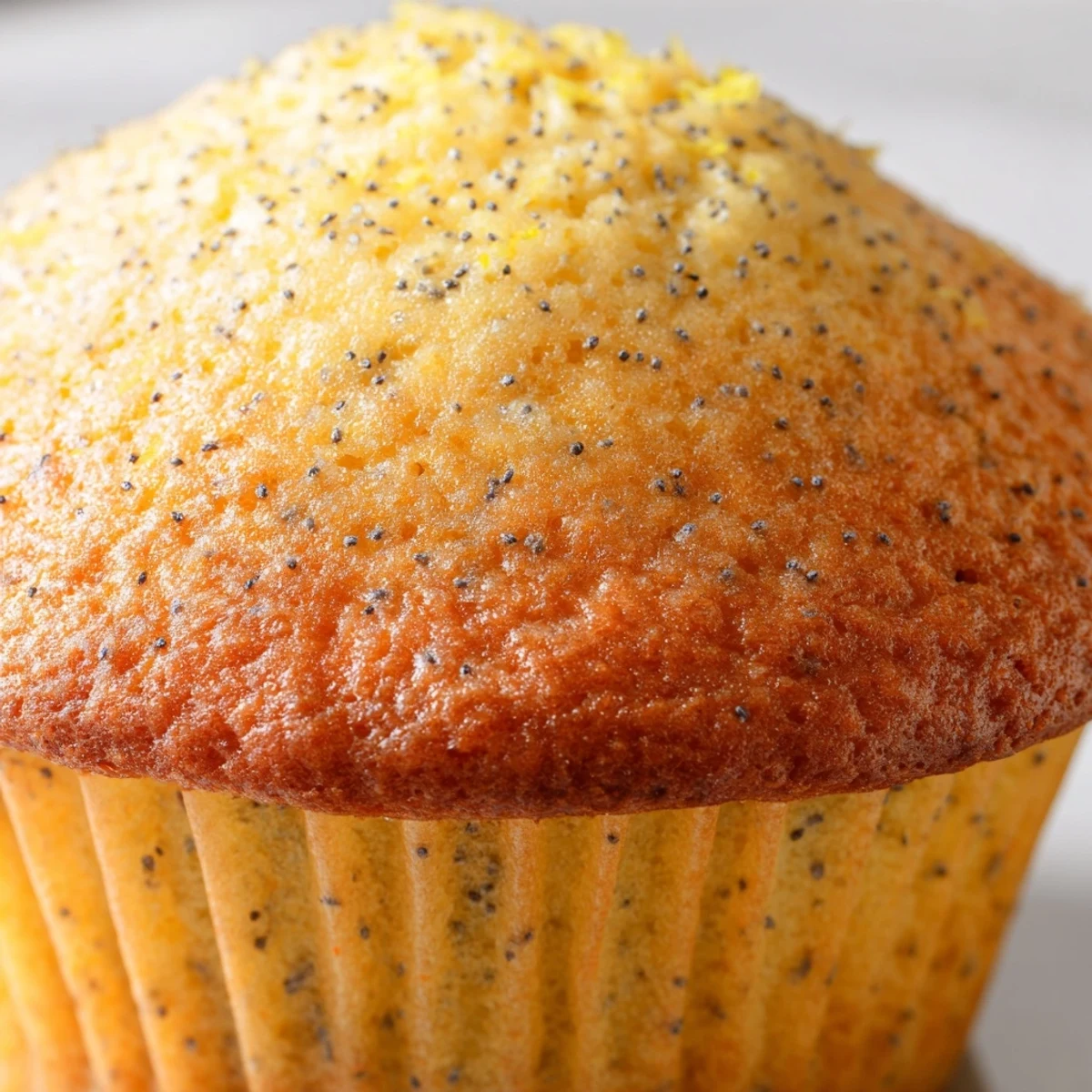Moist lemon poppy seed muffins studded with tiny black seeds beside a bowl of fresh lemons