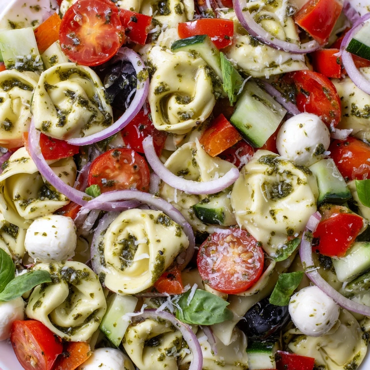 Creamy cheese tortellini salad tossed with fresh mozzarella, black olives, and vibrant vegetables in Italian vinaigrette