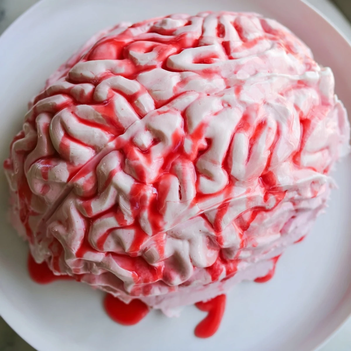 Slice of no bake strawberry cheesecake brain oozing red coulis over cookie crust