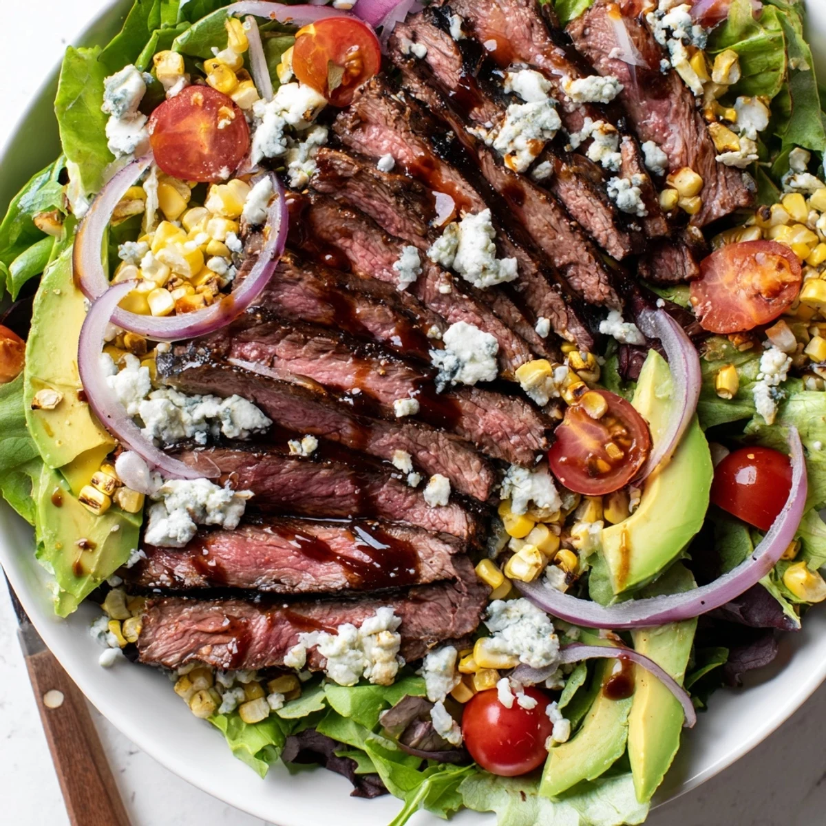 Juicy sliced balsamic steak arranged over a vibrant Gorgonzola salad with grilled corn
