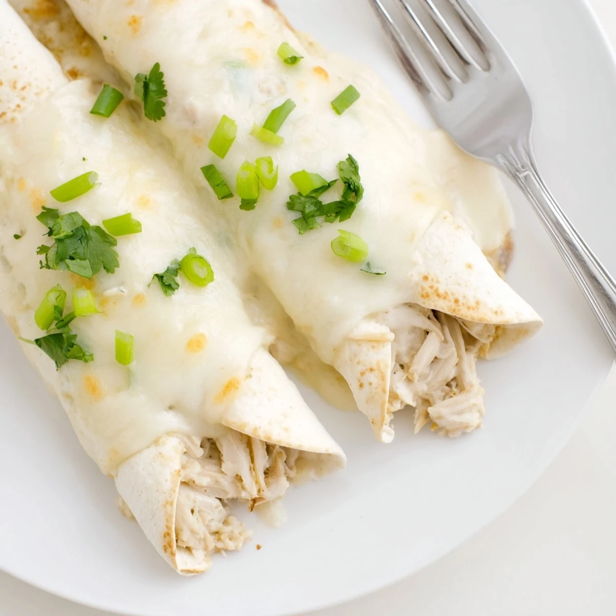 Creamy White Chicken Enchiladas bubbling golden, velvety sauce, melted cheese, garnished cilantro