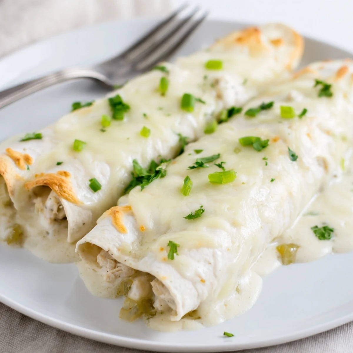 Warm Creamy White Chicken Enchiladas sliced on plate, steam rising, cilantro garnish